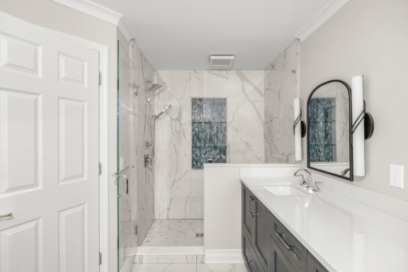 Modern bathroom with a glass shower, marble walls, and a stylish double vanity.